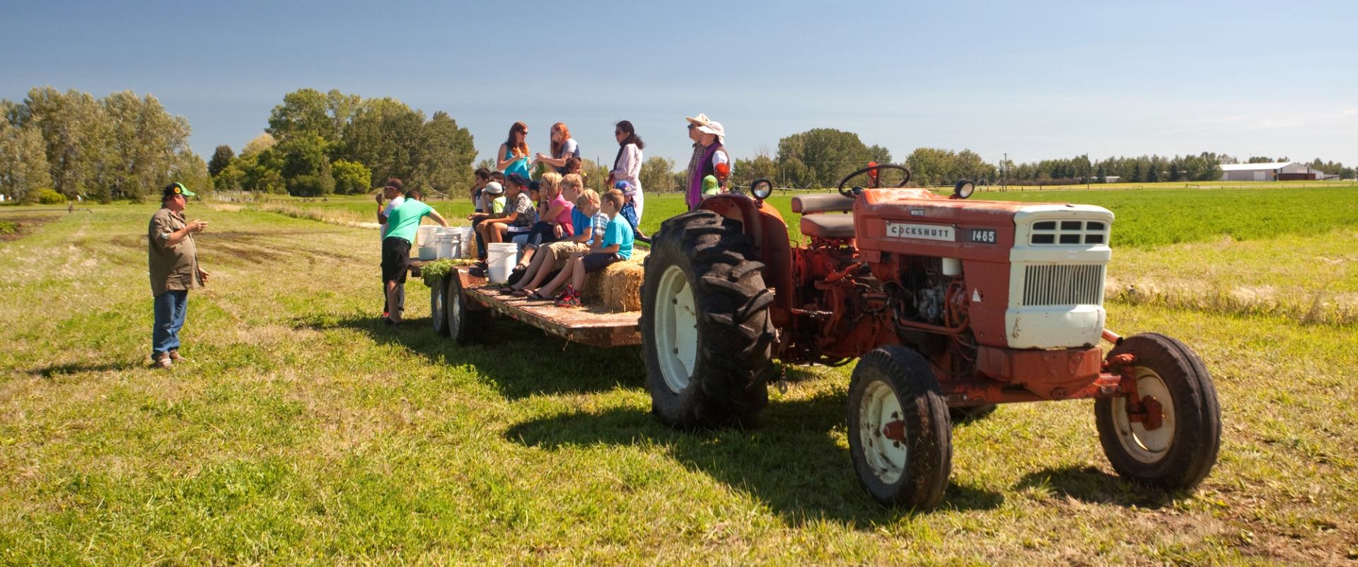 Visitors standing on a tractor trailer participating in Alberta Open Farm Days