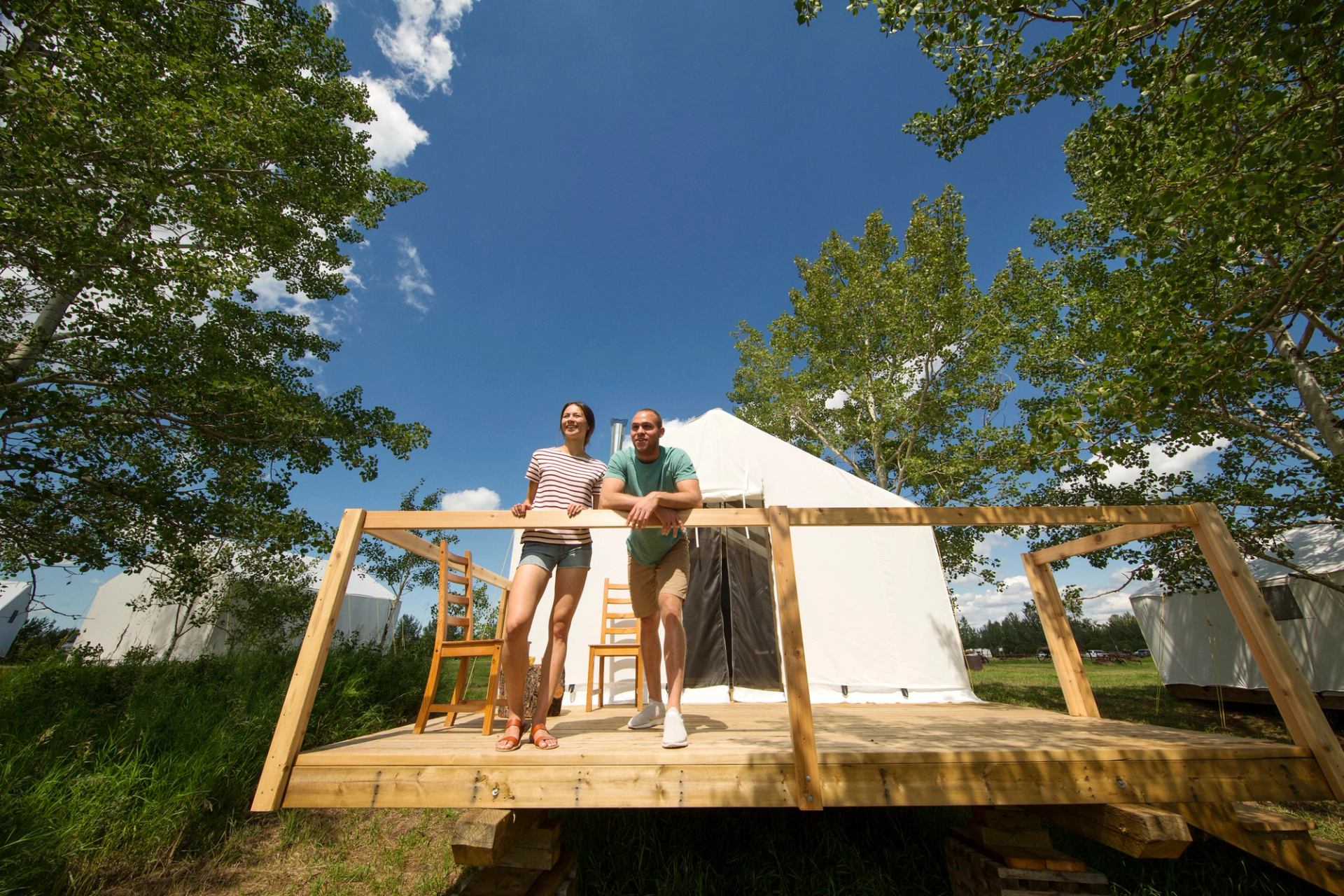 Couple outside a trapper tent at Metis Crossing. Comfort Camping on the shores of the North Saskatchewan.