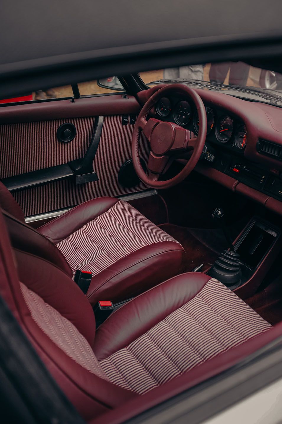 Interni bordeaux di una Porsche classica con sedili coordinati e plancia rivestita nello stesso tono.