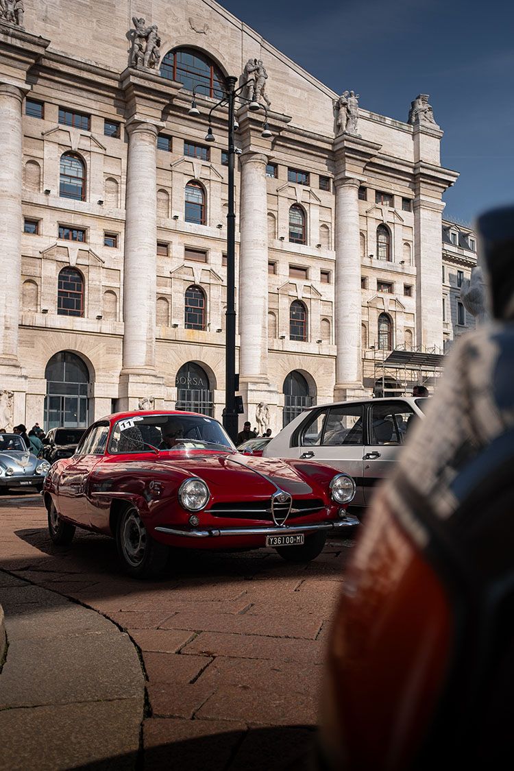 Alfa Romeo classica rossa in Piazza Affari a Milano, davanti alla facciata monumentale della Borsa.
