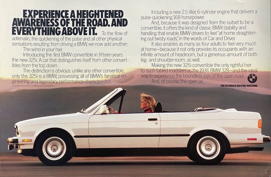 Vintage BMW advertisement featuring a white BMW 325i Convertible with a woman driving, her hair blowing in the wind. The headline reads 'Experience a heightened awareness of the road. And everything above it.' It emphasizes the car's unique appeal as the first BMW convertible in fifteen years and highlights its 2.5-liter, 6-cylinder engine with 168 horsepower. The tagline 'The Ultimate Driving Machine' anchors the bottom right corner.