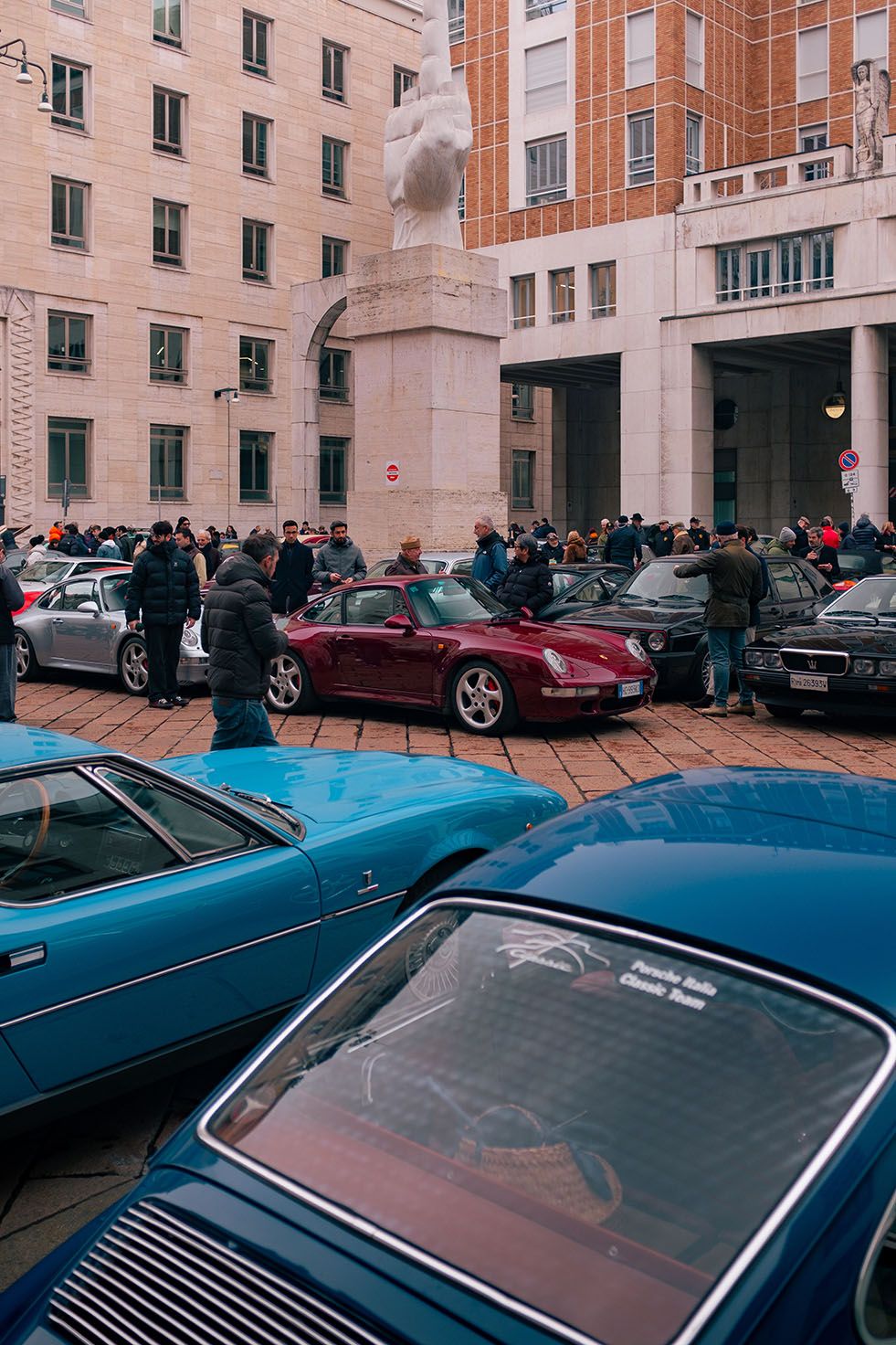 Raduno di auto d’epoca e sportive in Piazza Affari a Milano, con persone che osservano le vetture esposte.