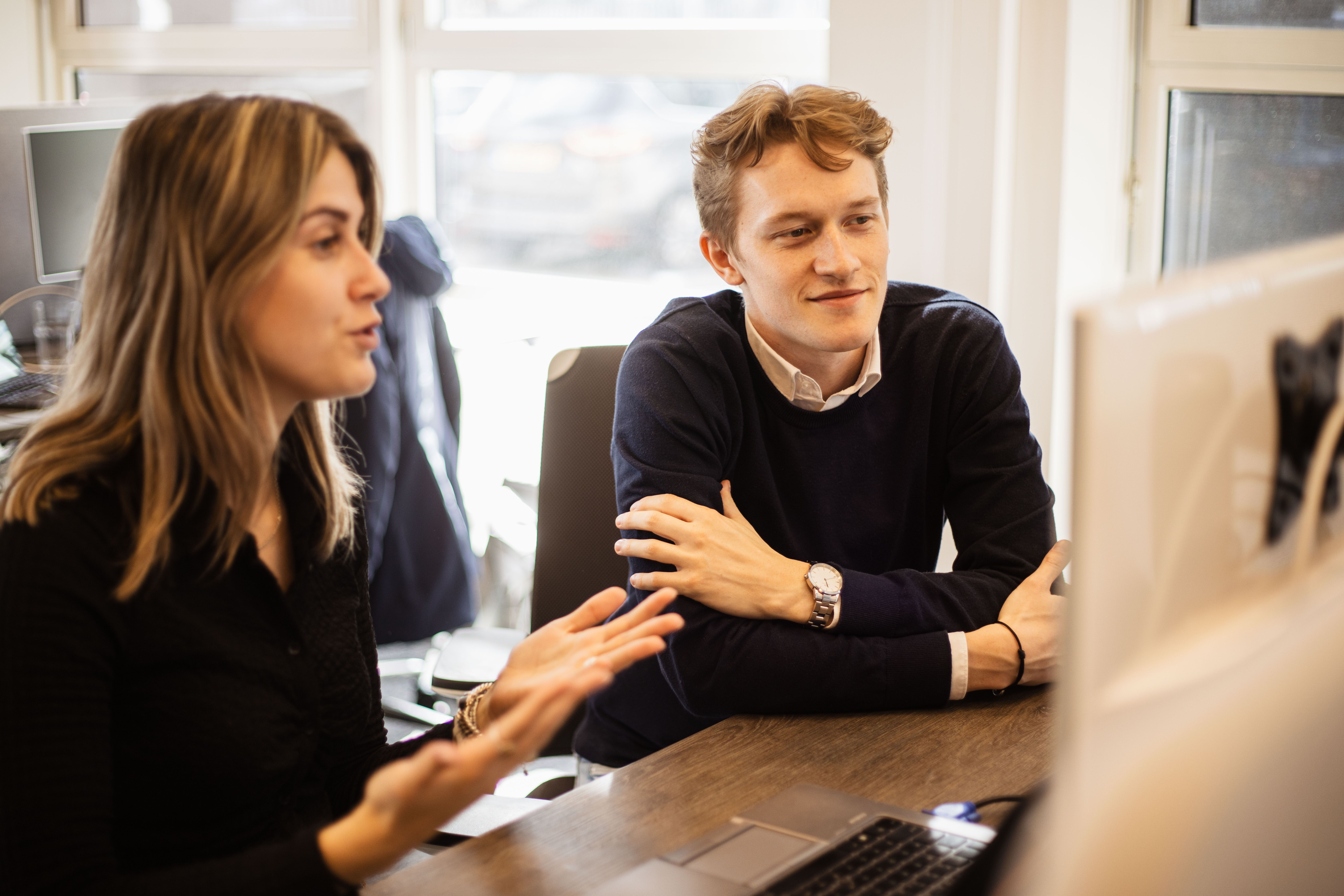 Twee mensen praten en kijken naar een computer