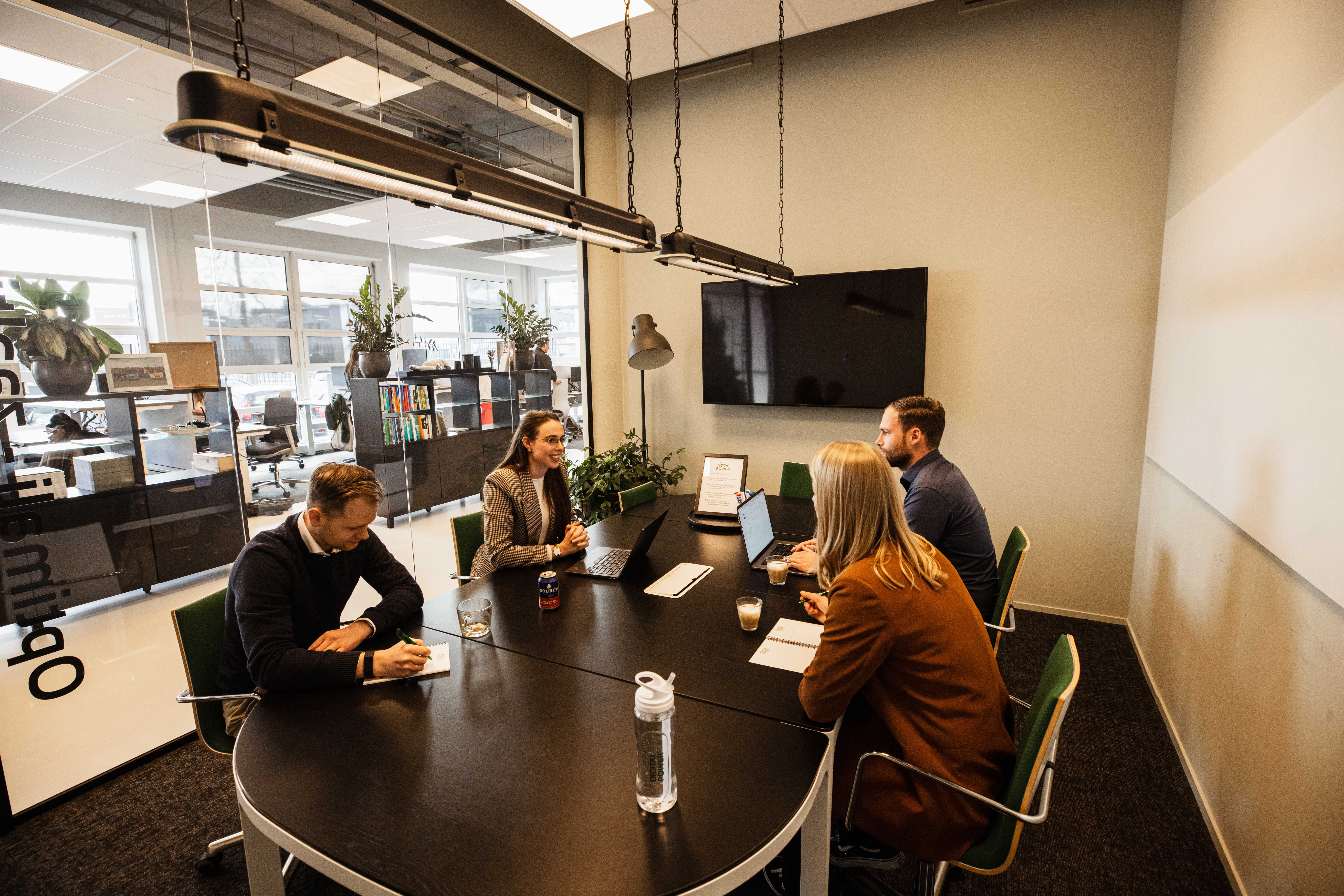 Four people in a meeting room discussing projects and products