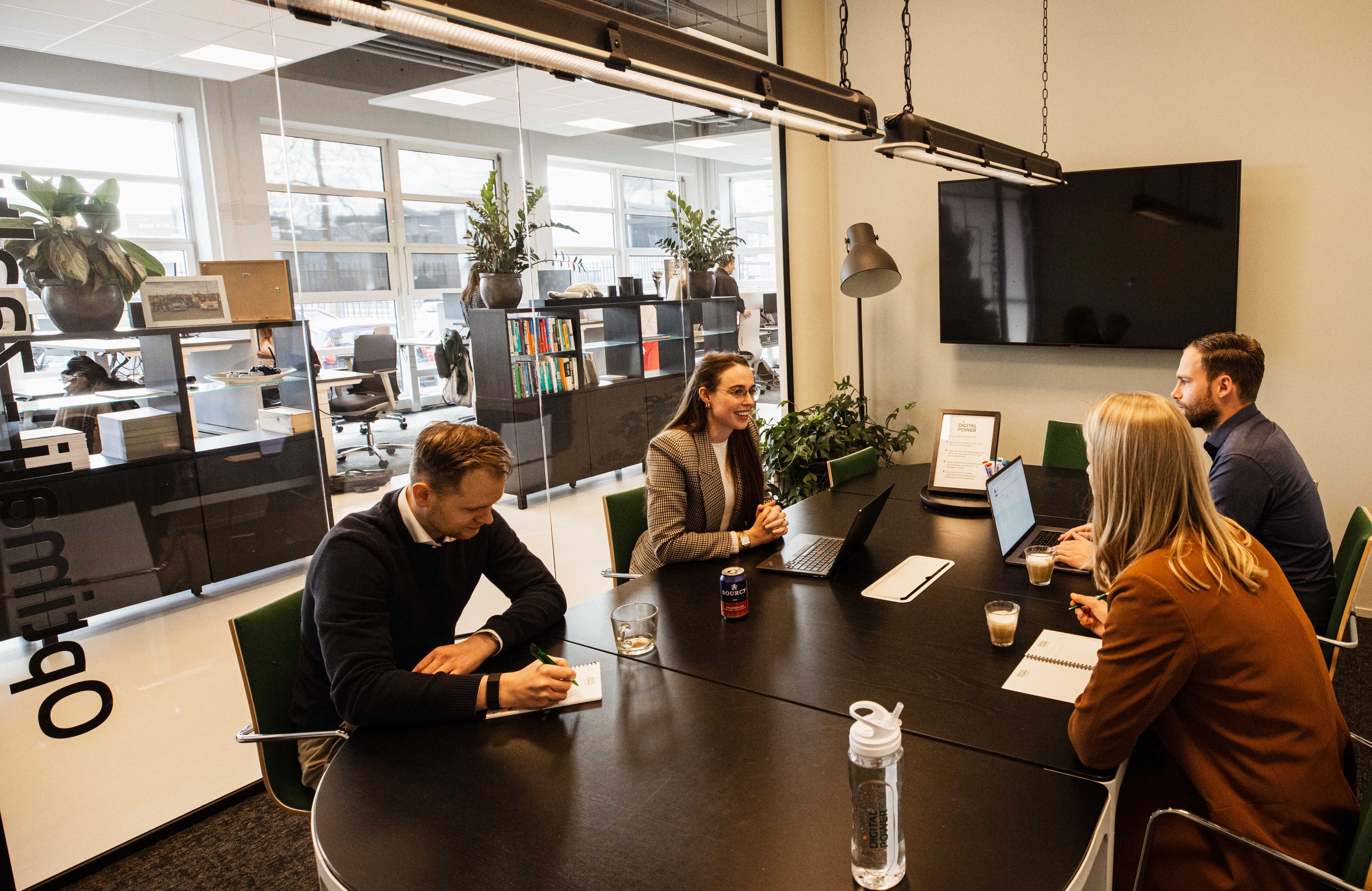 Four people in a meeting room discussing projects and products