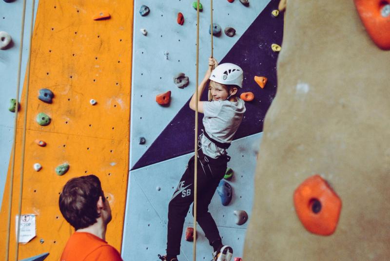 a child figuring out the right approach on the climbing wall