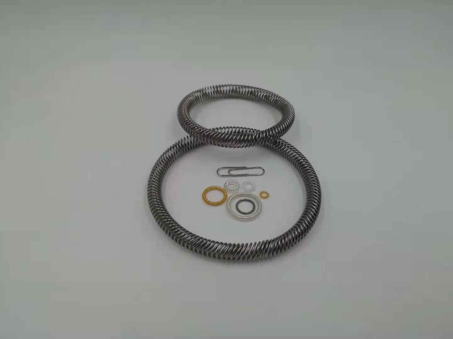 Various sizes of canted coil spring rings with paperclip for scale comparison