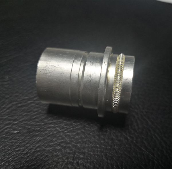 Machined cylindrical metal connector socket with external canted coil spring ring and retention flange
