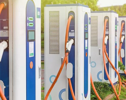 Row of commercial electric vehicle charging stations with heavy-duty orange high-power charging cables