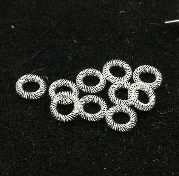Silver-plated canted coil spring contact rings clustered on a dark background