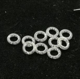 Group of silver-plated canted coil spring contact rings on a black background