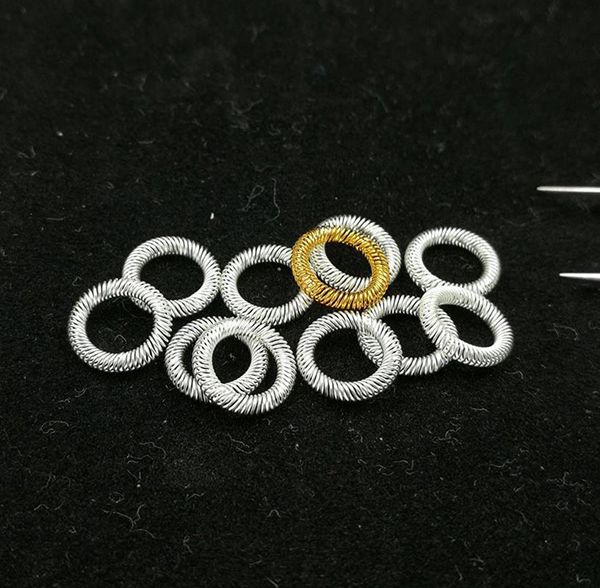 Silver-plated and gold-plated circular canted coil spring contact rings on black surface