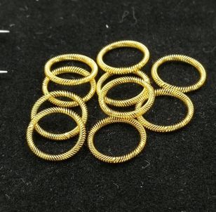 Cluster of small gold-plated canted coil spring rings overlapping on black fabric surface