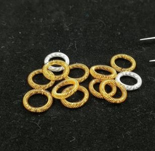 Gold-plated and silver-plated circular canted coil spring contact rings on dark surface