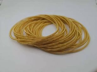 Gold plated canted coil spring contact rings stacked loosely on a white surface