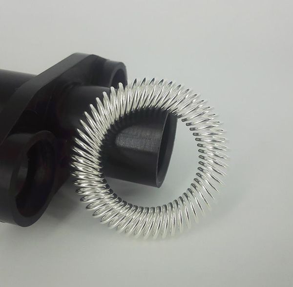 Silver-plated canted coil spring ring displayed alongside a black electrical connector housing component