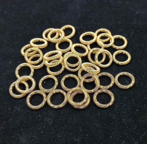 Gold-plated circular canted coil spring contact rings scattered on a black background