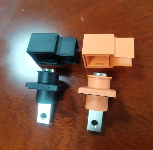 High-voltage connector terminals with black and orange insulated housings and busbar connection tabs