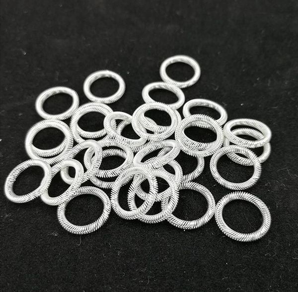 Pile of silver-plated canted coil spring rings on a dark background