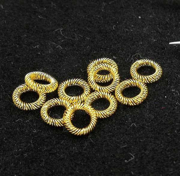 Gold-plated canted coil spring contact rings loose on a dark fabric background