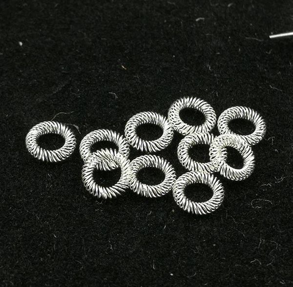 Silver-plated canted coil spring contact rings loose on a dark surface