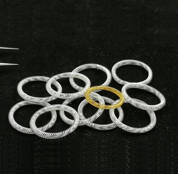 Silver-plated and gold-plated canted coil spring contact rings on a black background