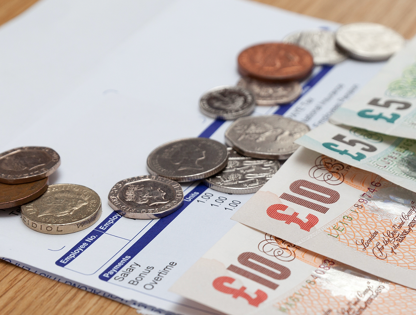 payslip with pound coins and pound notes on top.