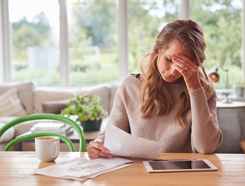 Young woman at her kitchen table looking at bills