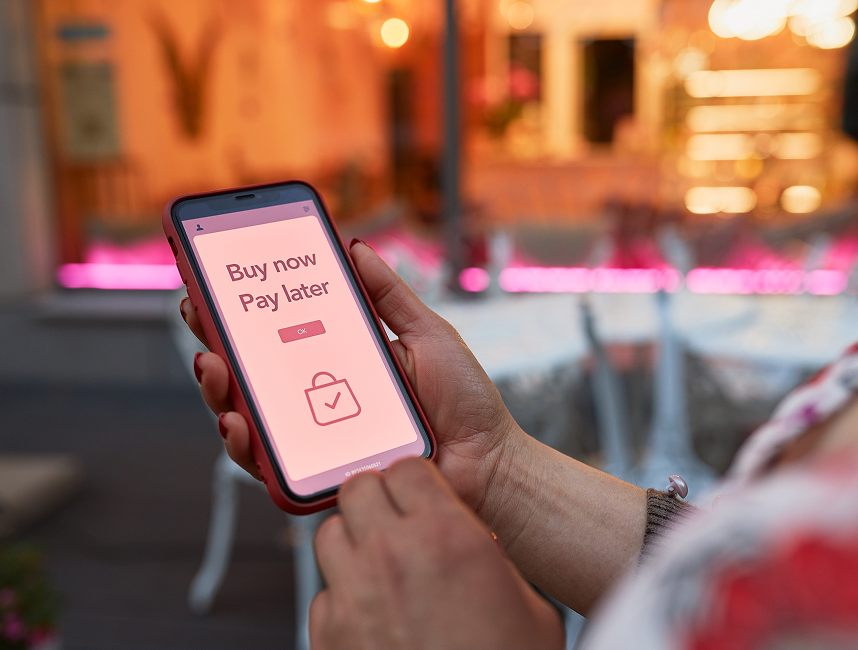 person holding phone with a shopping notification on the screen that confirms they've bought something and will pay later