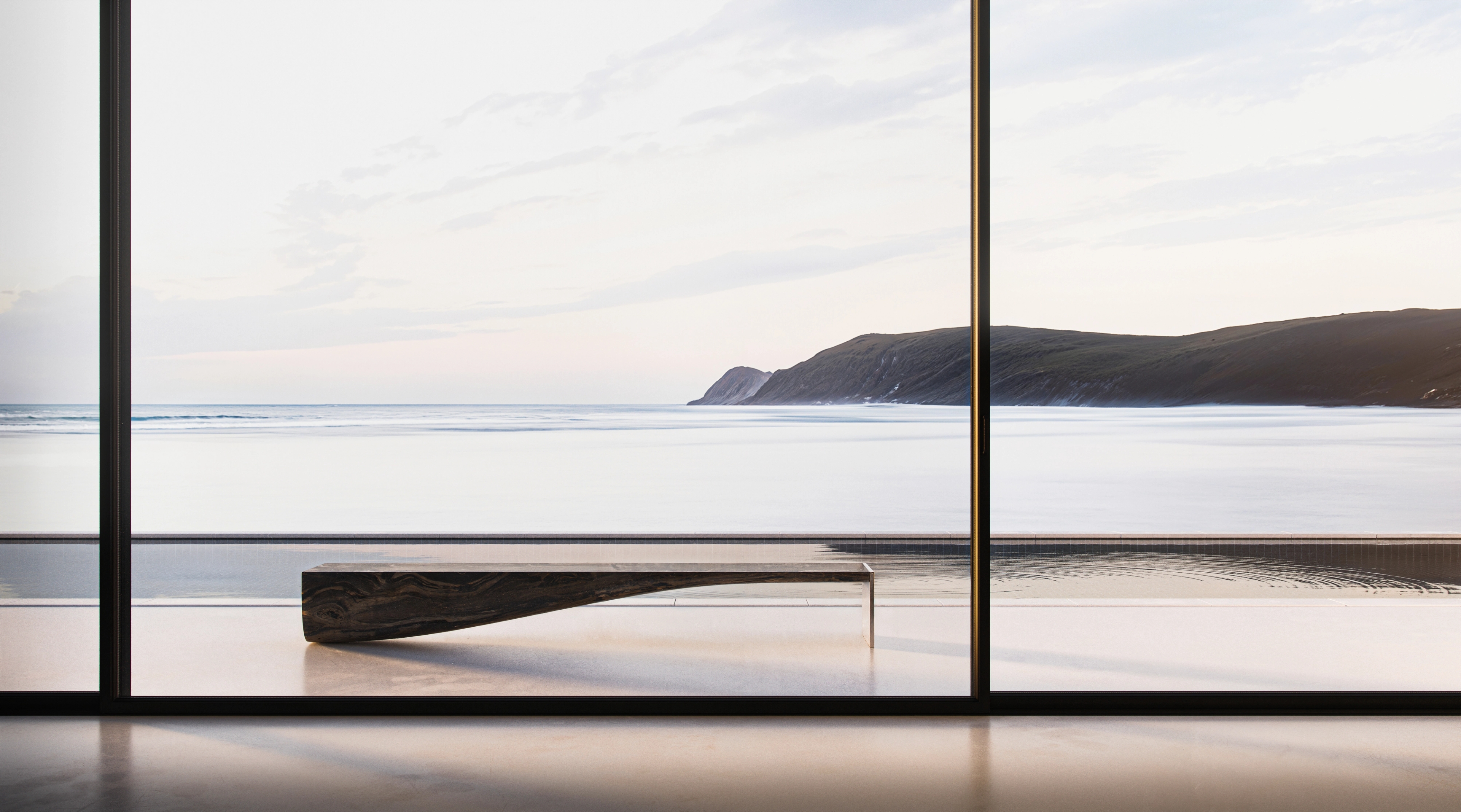 Living space framed by large-scale glazing overlooking the coastline