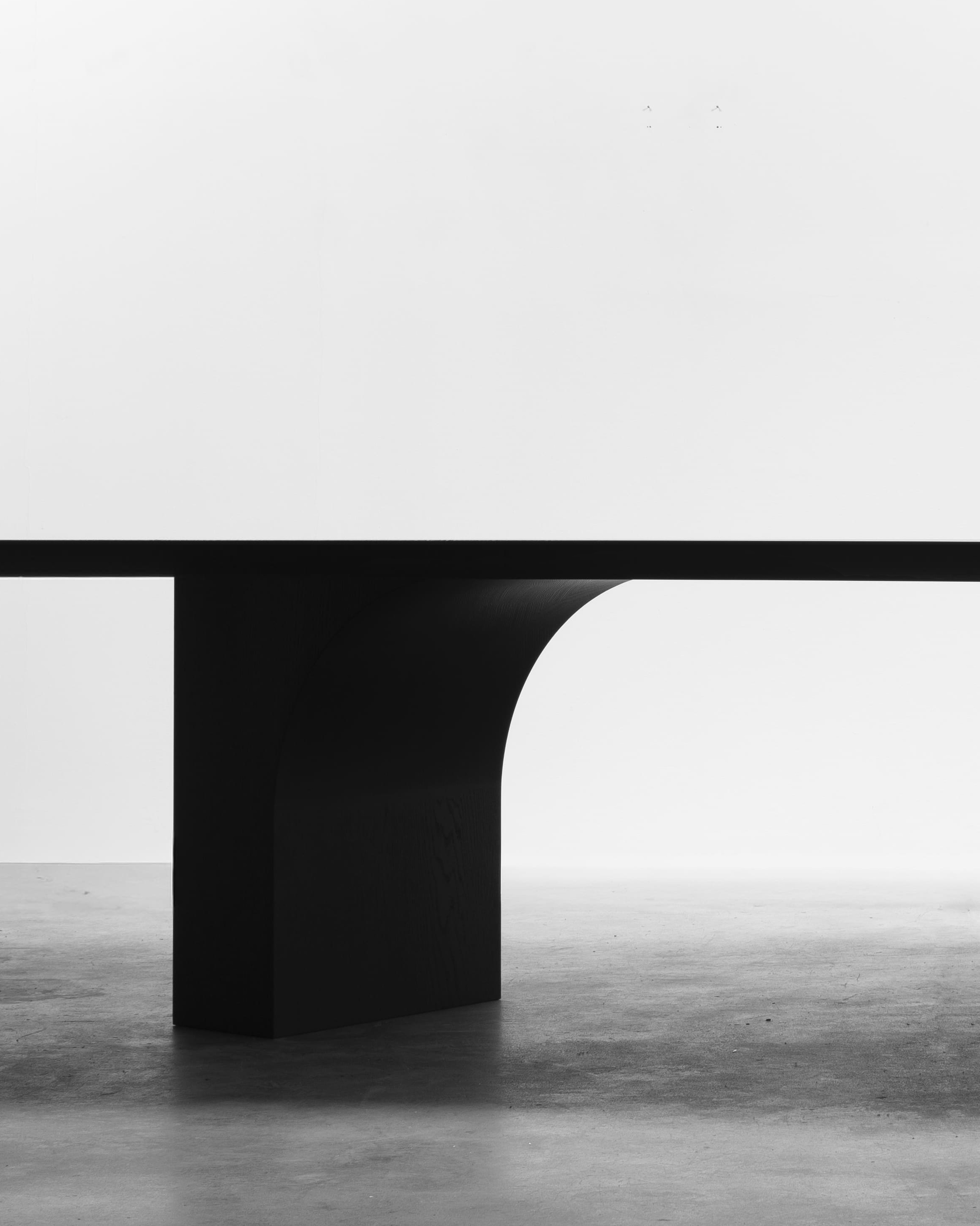 Monolithic oak dining table with a sculptural architectural form