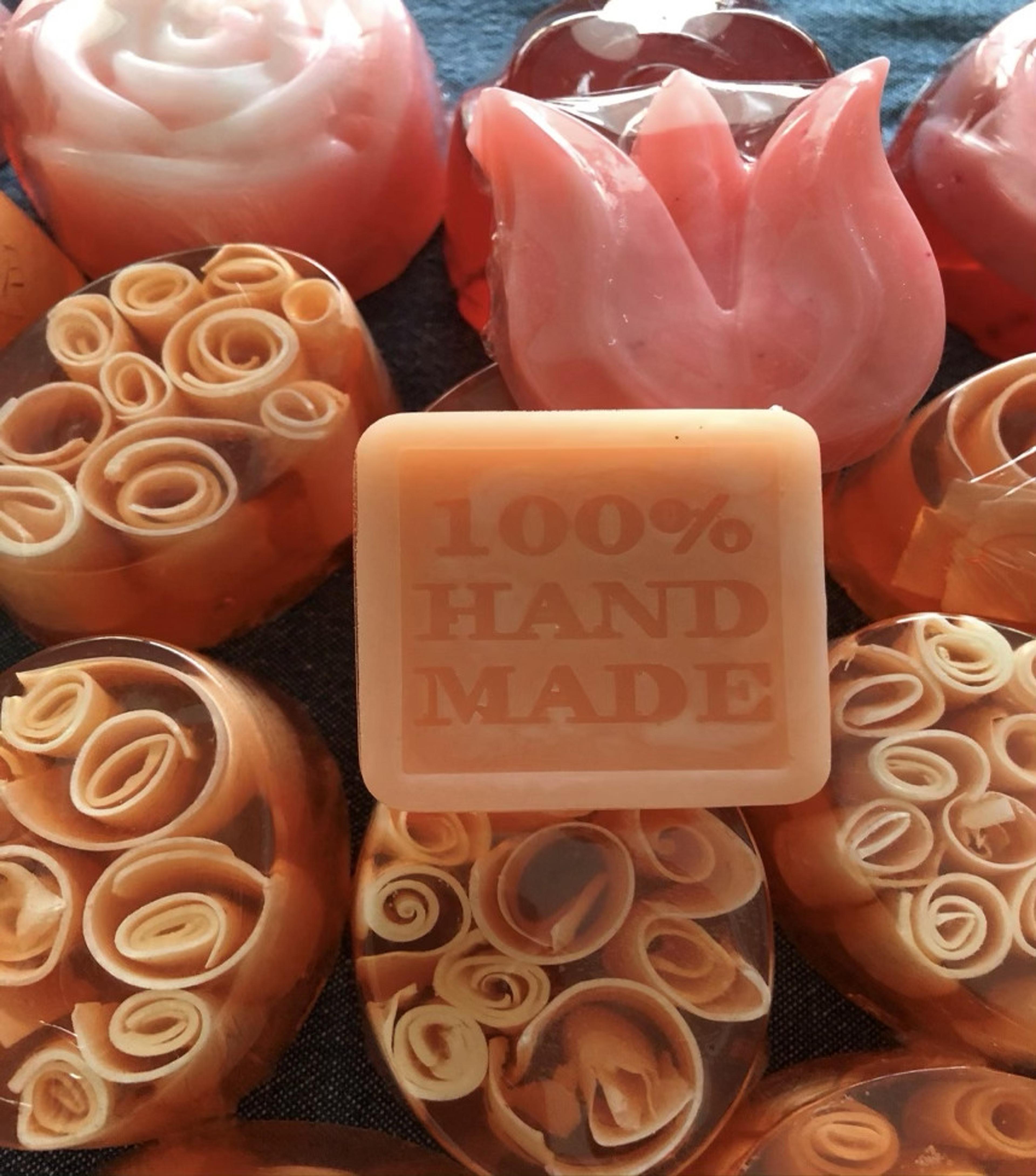 Ovalados con rulos de leche de cabra junto a un jabón con la leyenda 100% hand made
