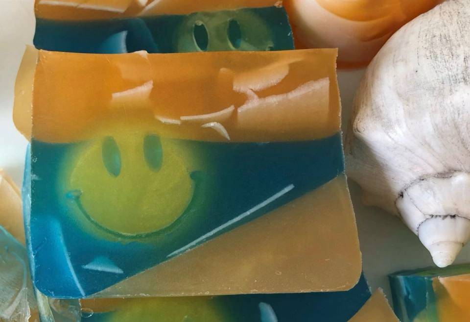 Jabón en capas naranja y azul con un sol sonriente