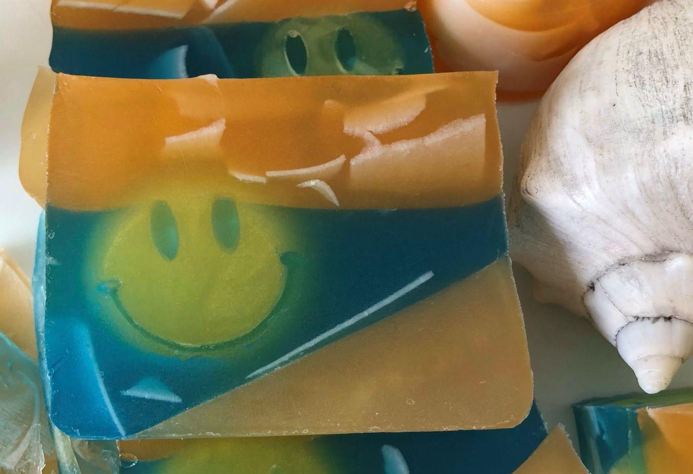 Jabón en capas naranja y azul con un sol sonriente