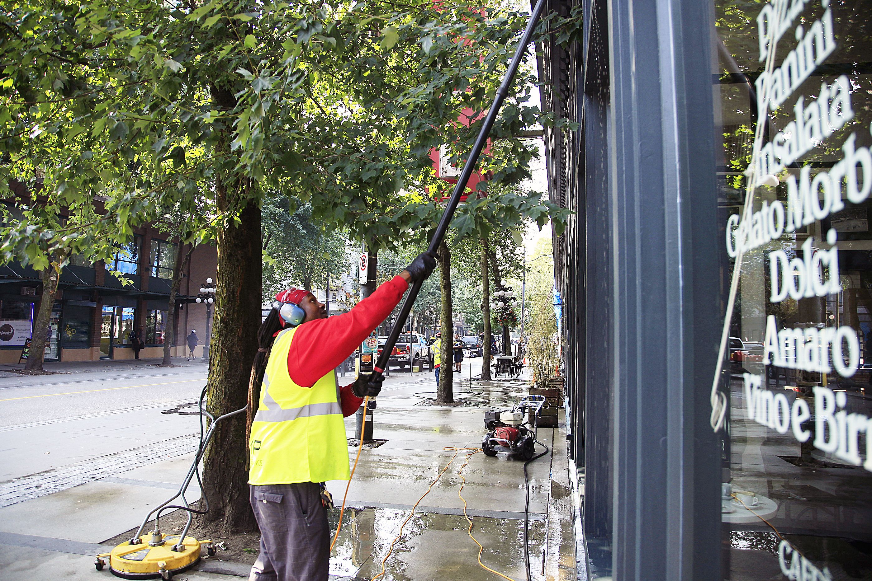  a man pressure washing and cleaning a store window