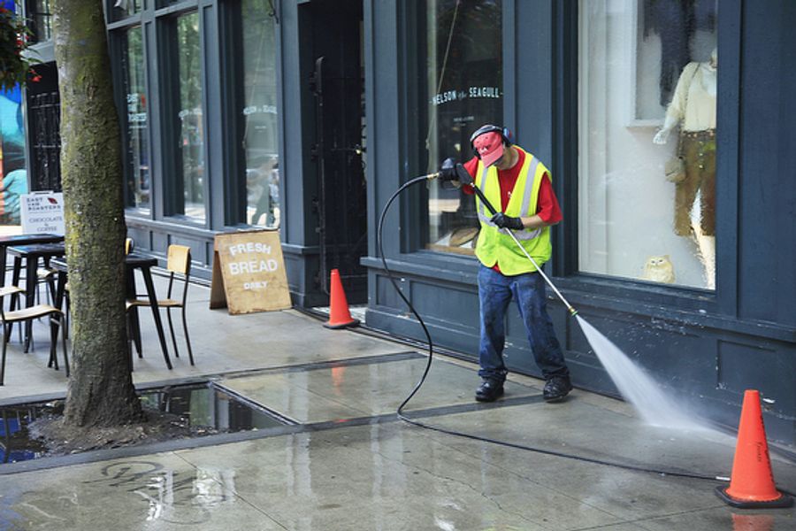 Powerwashing sidewalk in front of business