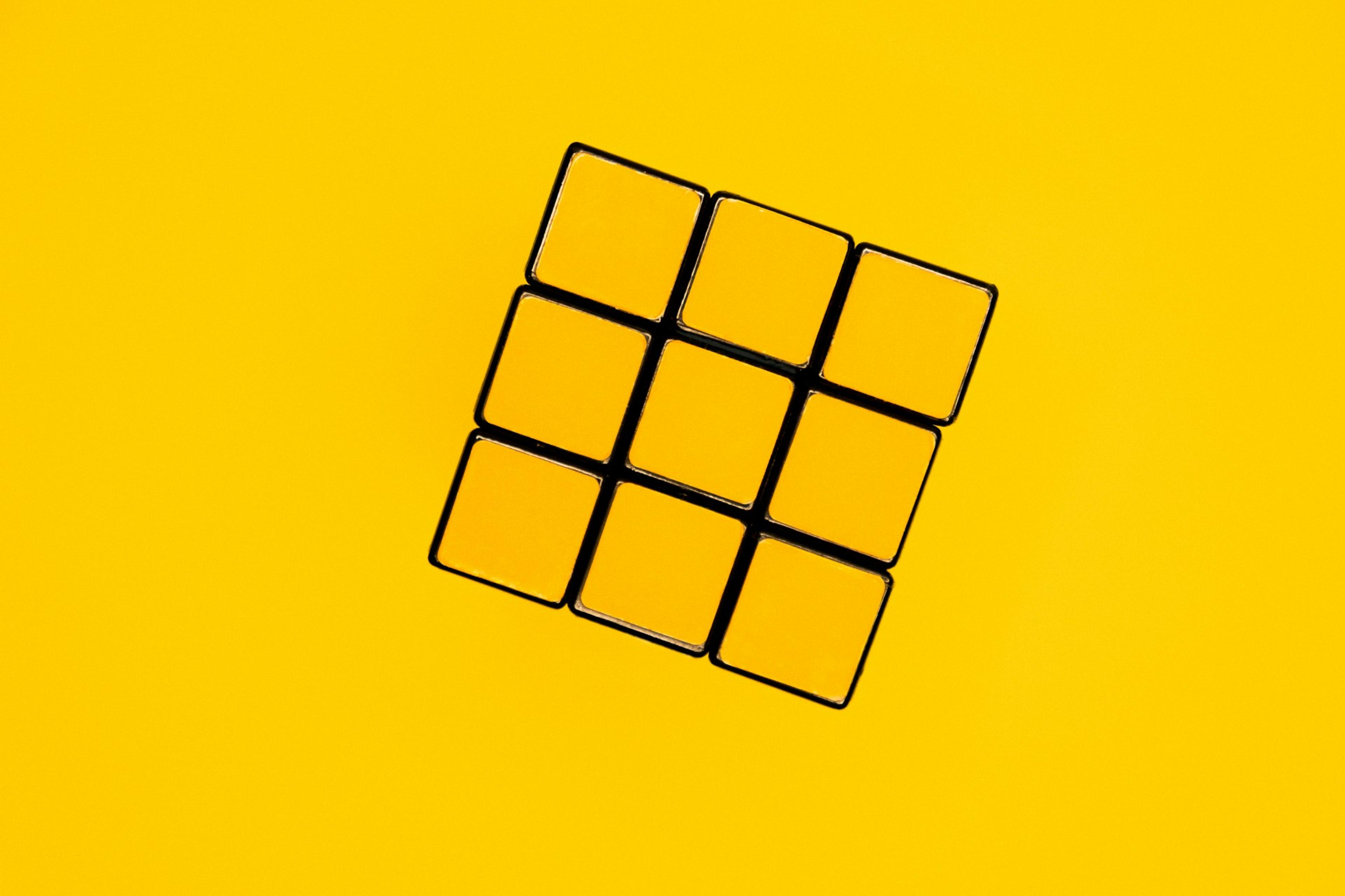A solved Rubix Cube on a yellow background