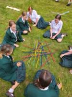 Girls enjoy a game of Pick Up Sticks on the lawn.