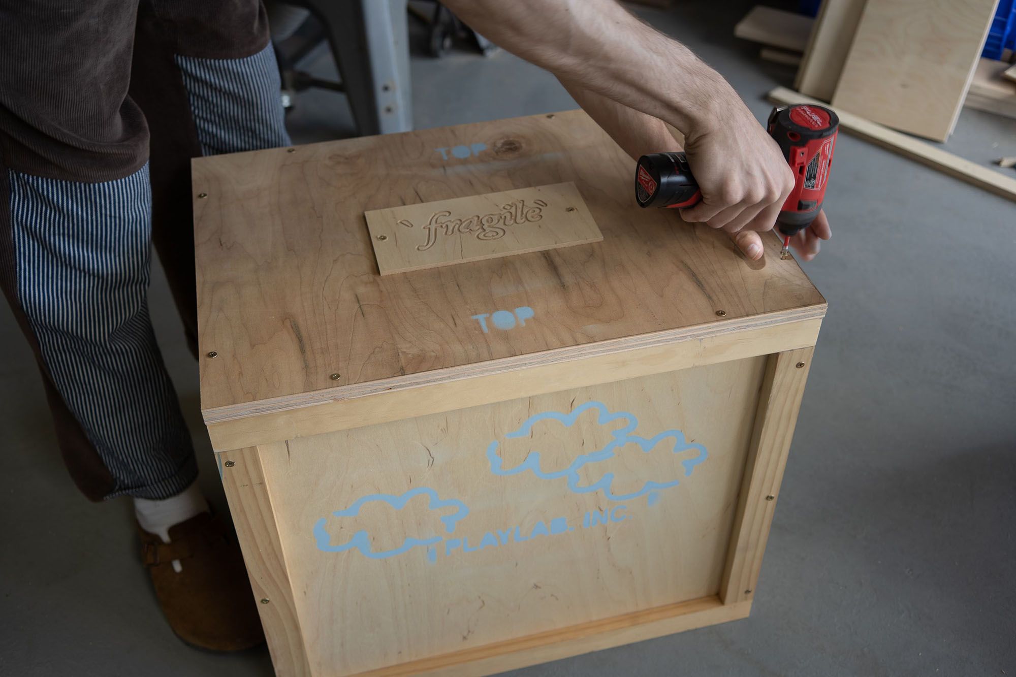 Person using a drill to screw a lid on a wooden crate