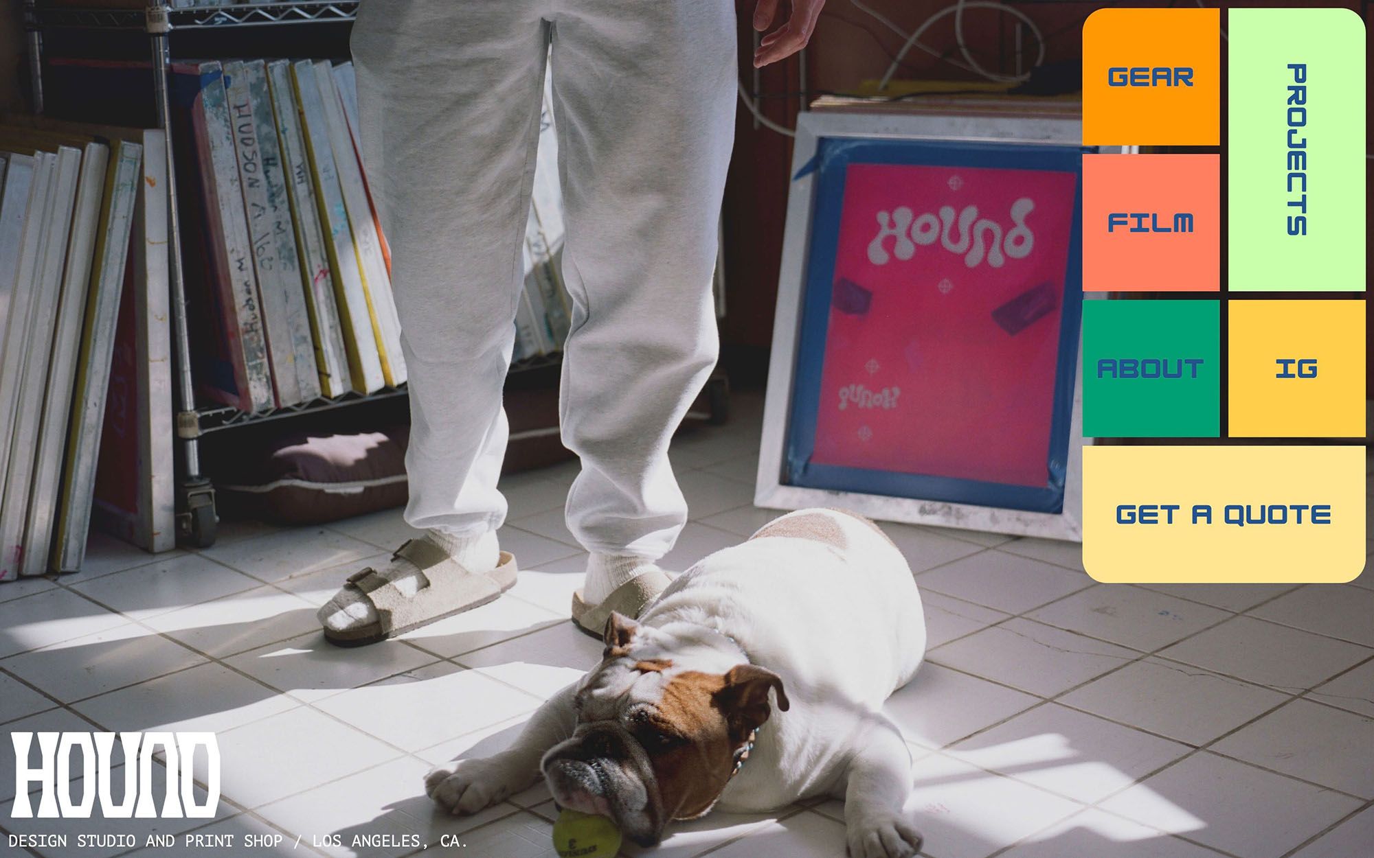 Desktop home page from hounded.co. Background image shows dog laying on floor of print shop.
