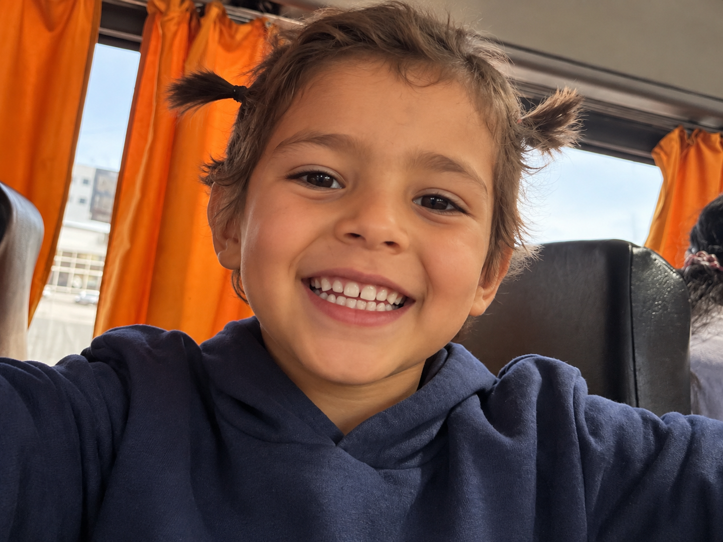Une enfant sourit à l’objectif dans un bus