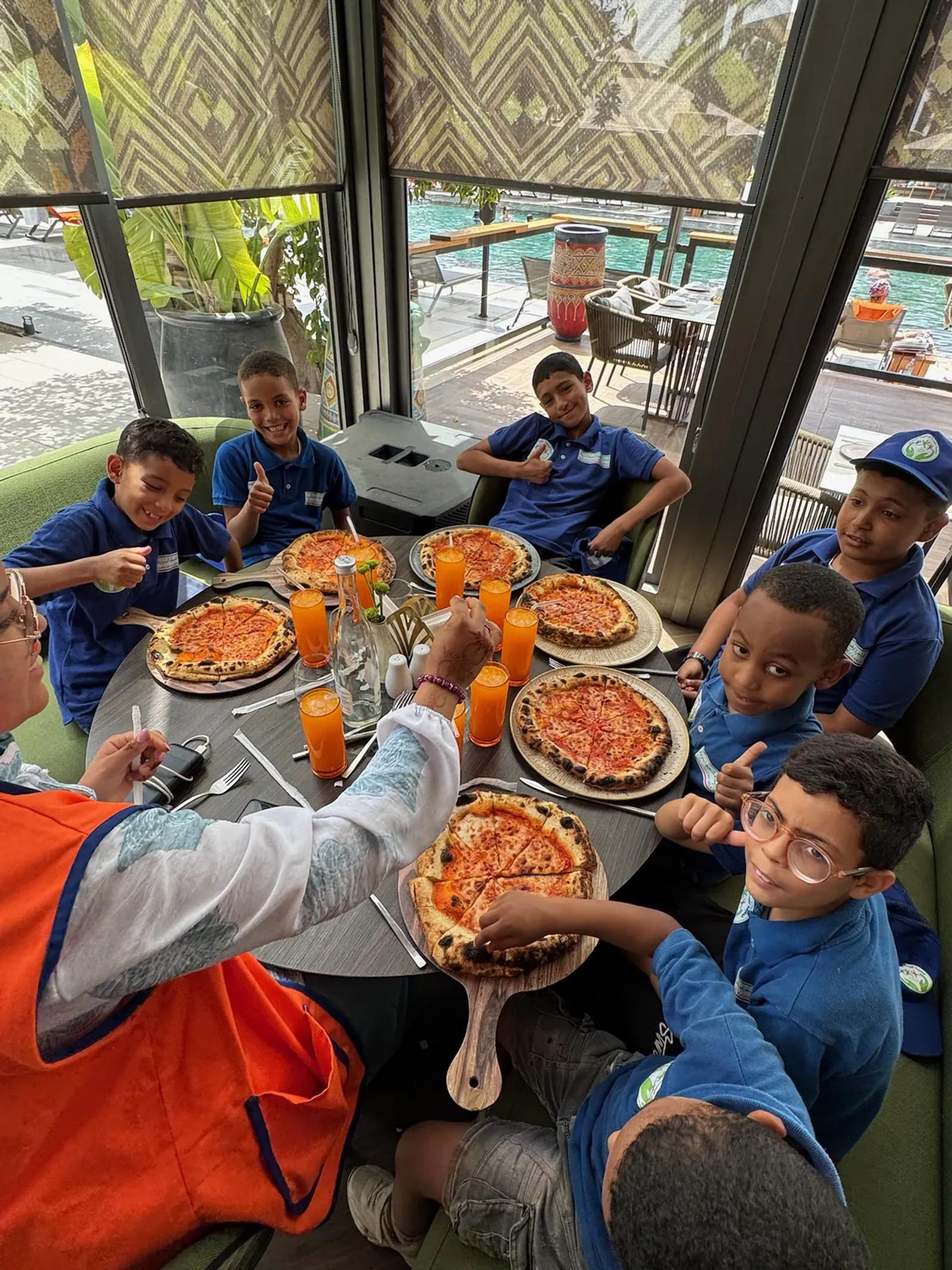 Des enfants partagent des pizzas autour d’une table