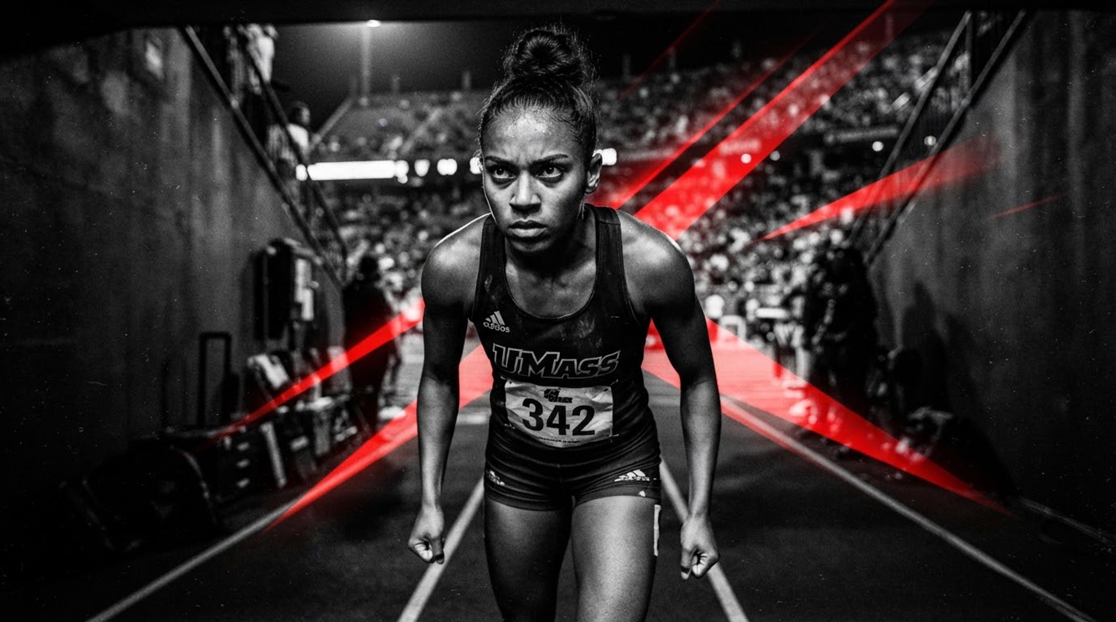 A collegiate sprinter set in the blocks under hard red stadium light.