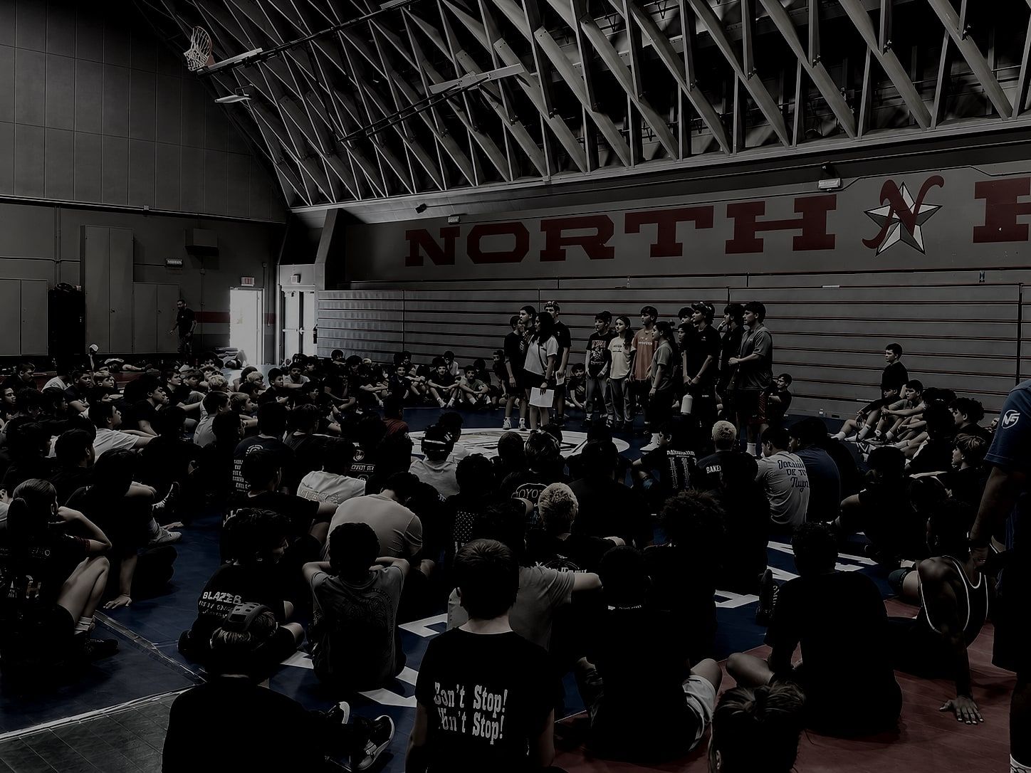 Several hundred student-athletes seated on a gym floor, listening to a MindGame Movement assembly.