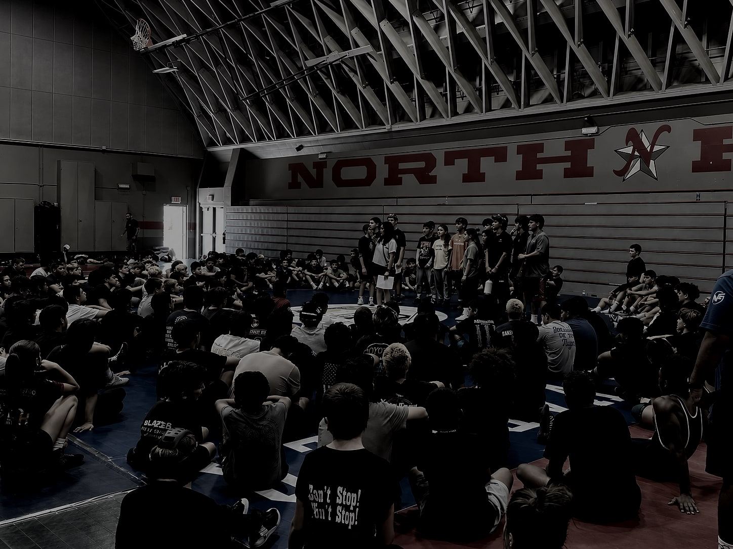 Several hundred student-athletes seated on a gym floor, listening to a MindGame Movement assembly.