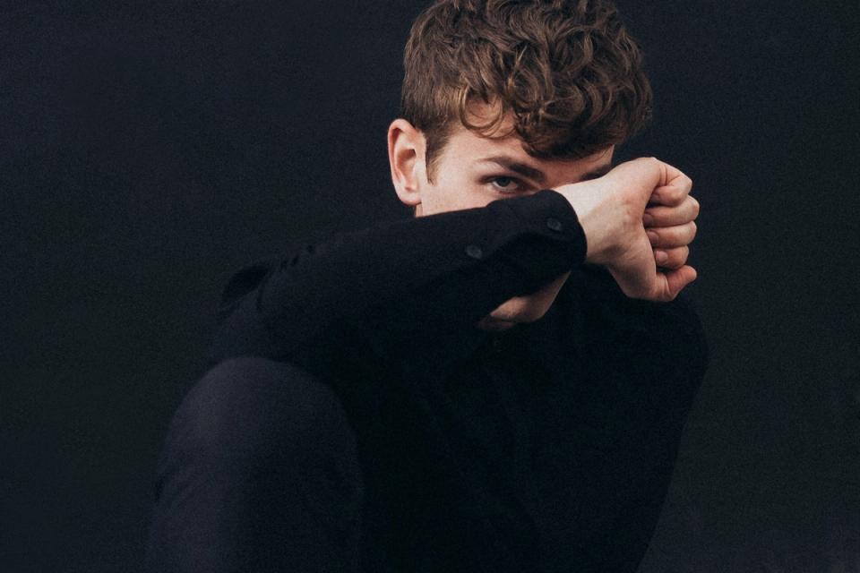 Portrait von Producer Delusion. Er versteckt sein Gesicht hinter seiner Hand