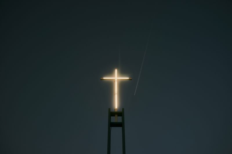 Glowing cross atop a tower at night