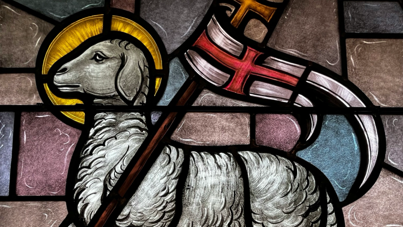Stained glass image of Christ as the conquering Lamb of God holding victory banners