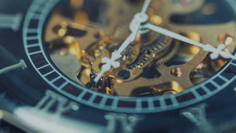A watch face with gears visible behind the minute and second hands.