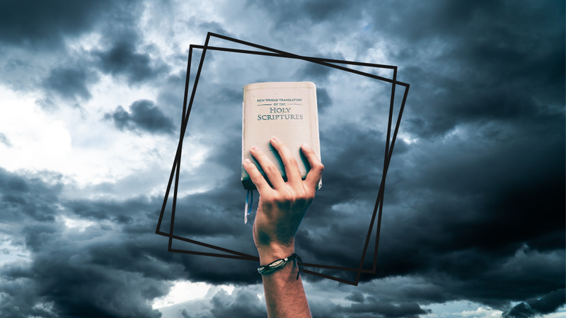 A small Bible being held up against a sky of dark clouds.